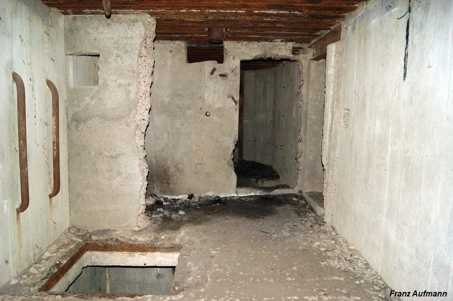 Fot. Pomieszczenie na skład amunicji i szyb łączący obie kondygnacje. W głębi wejście do izby bojowej. Za szybem zniszczona ściana działowa pomieszczenia dowodzenia.